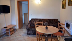 A compact living space with a sofa, a dining table, a TV, and a microwave. - Apartment Lenardic Bled (Bled)