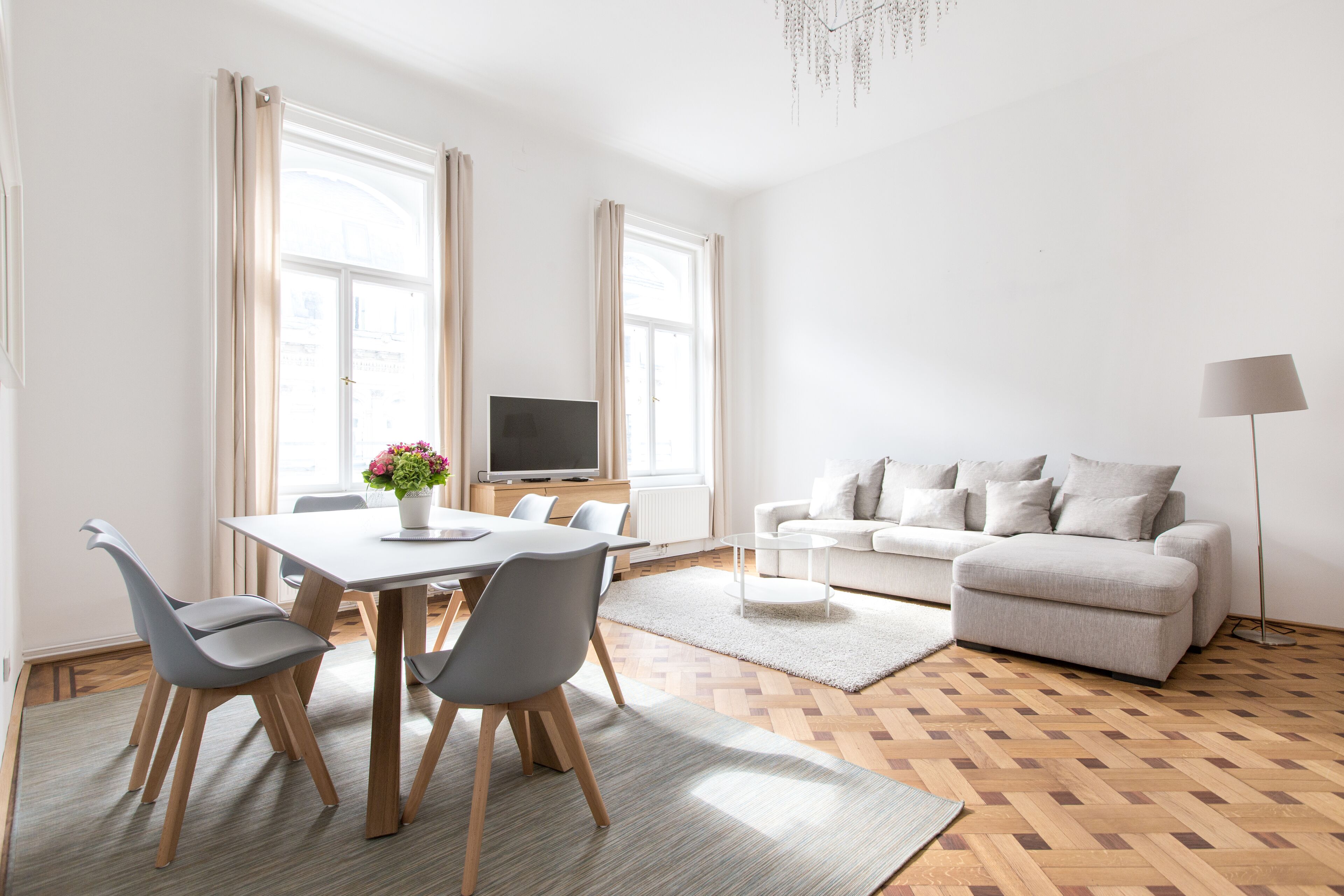 Een moderne woonkamer met een eethoek, een bank, een televisie en een lamp.
