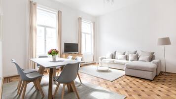 Een moderne woonkamer met een eethoek, een bank, een televisie en een lamp.