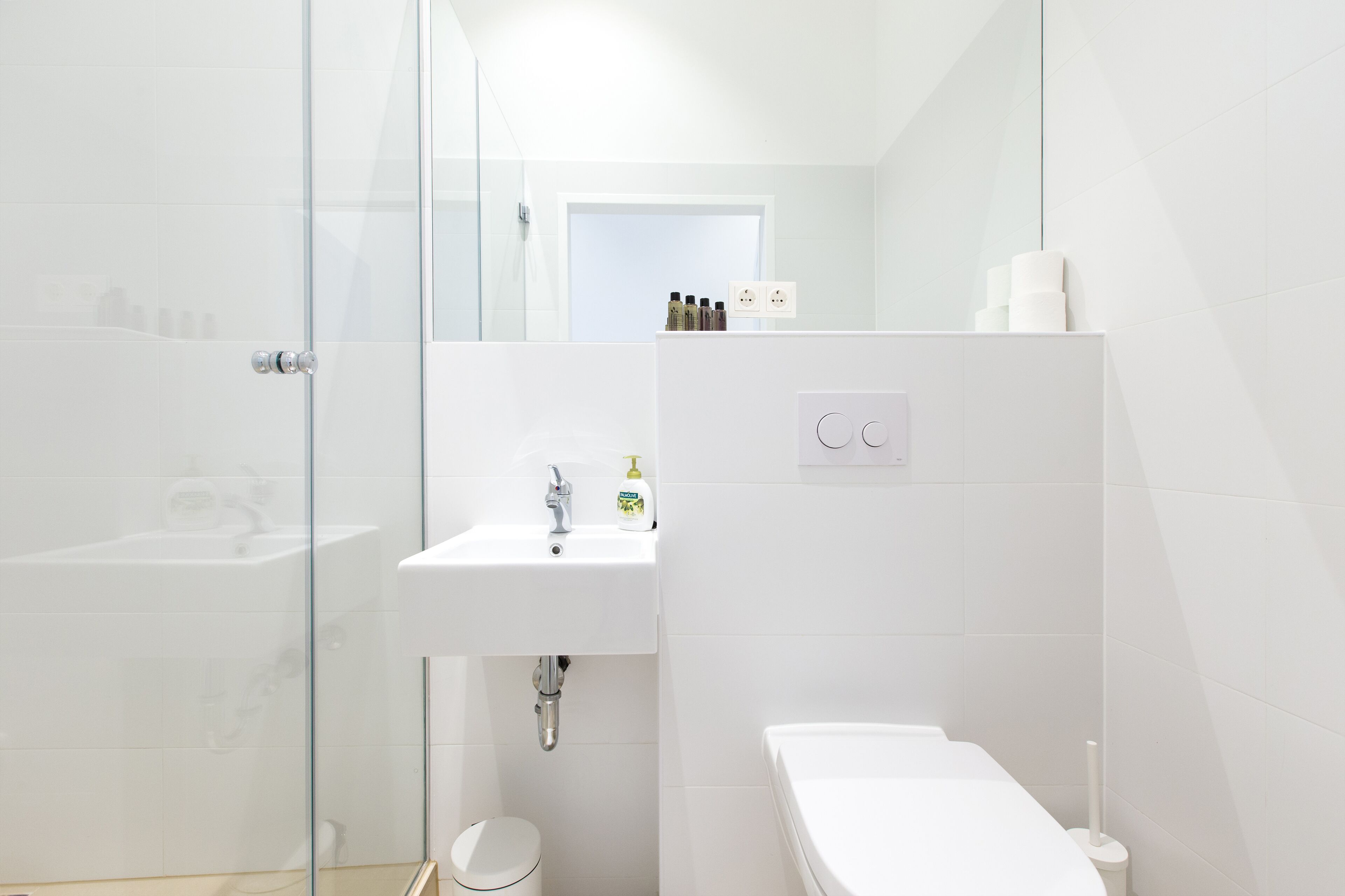 A modern bathroom with a glass shower enclosure, a white sink, and a toilet.