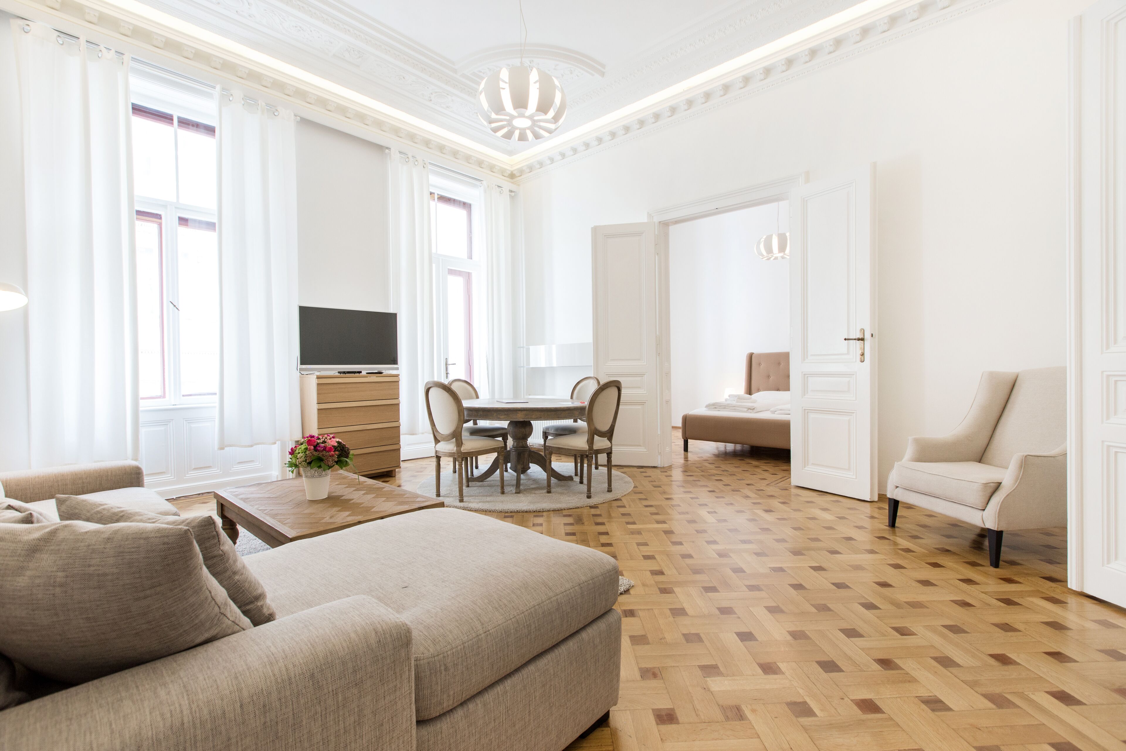 En rummelig stue med en stor sofa, et spisebord med stole og et fjernsyn.
