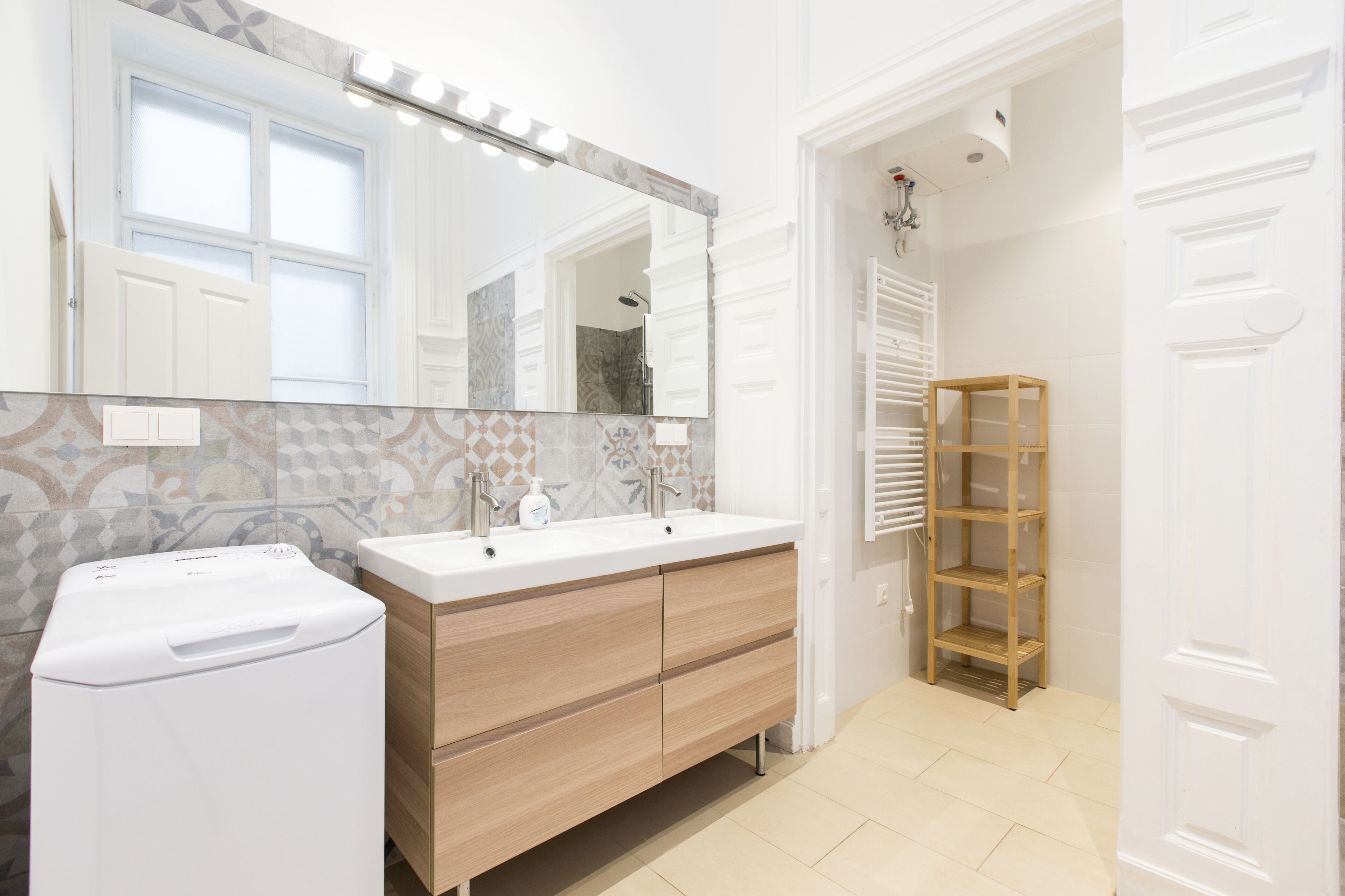 A modern bathroom with a double sink vanity, a large mirror, and a wooden shelf unit.