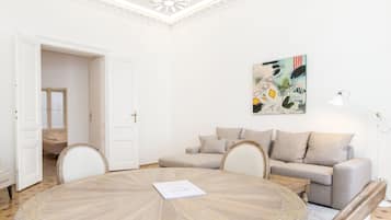 Une pièce avec une table ronde en bois, un canapé beige et un tableau accroché au mur.