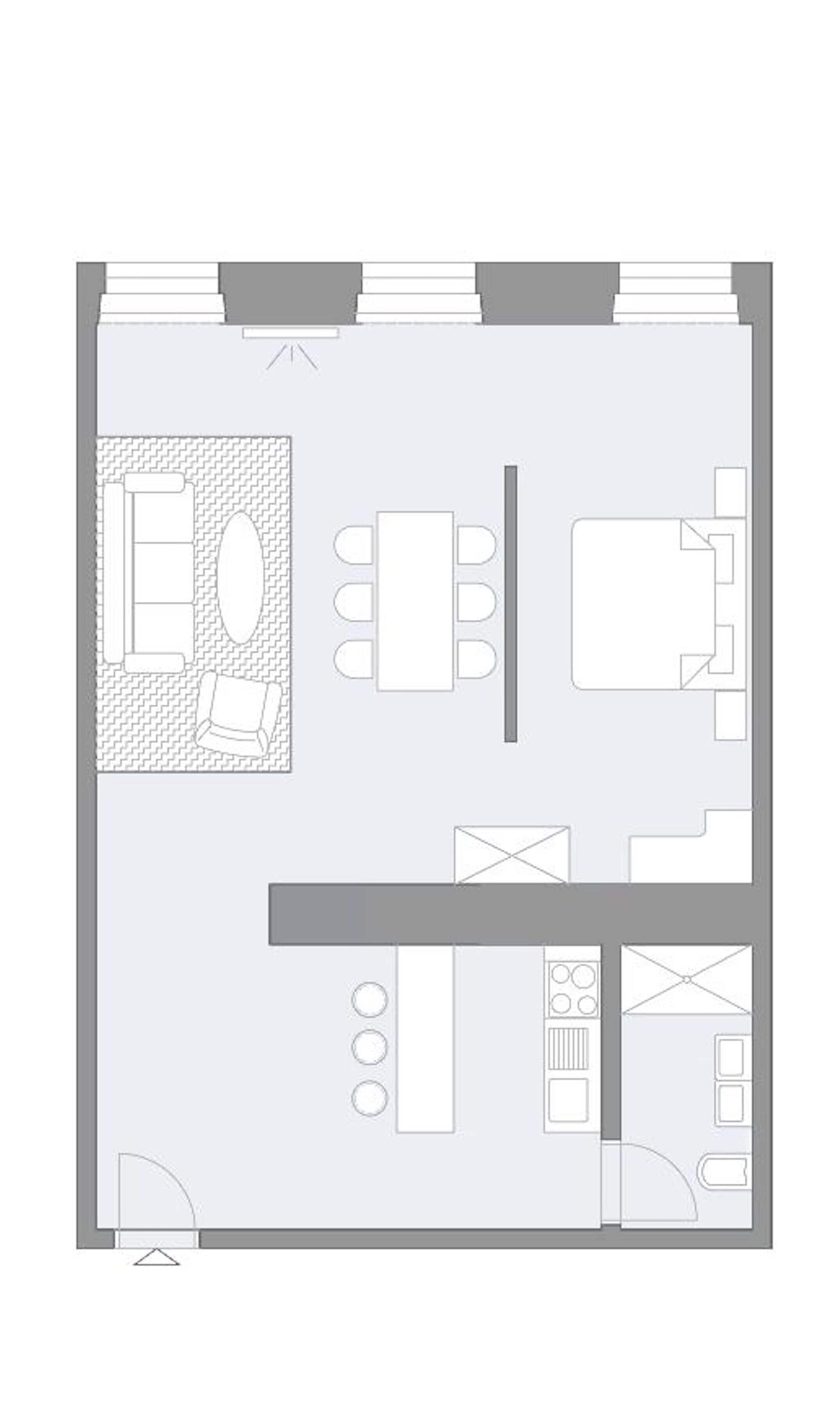 A floor plan of a hotel room with a bed, a sitting area with a sofa and a coffee table, a small kitchen area with a stove and sink, and a bathroom with a toilet and shower.