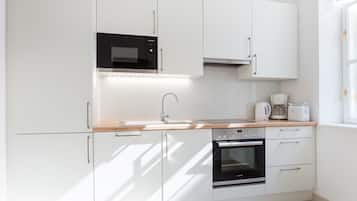 A modern kitchen with white cabinets, a microwave, a coffee maker, and an oven.