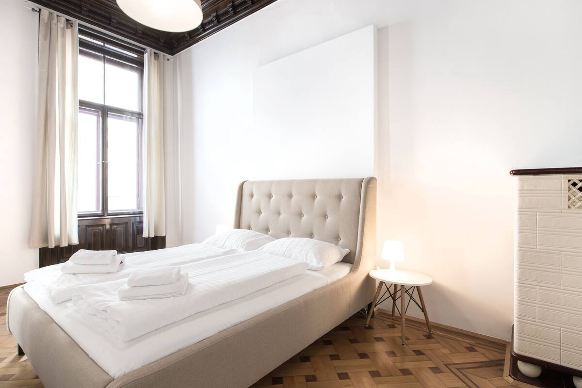 Hotellihuone, jossa on suuri sänky, pieni yöpöytä lampun kanssa ja vaatekaappi.