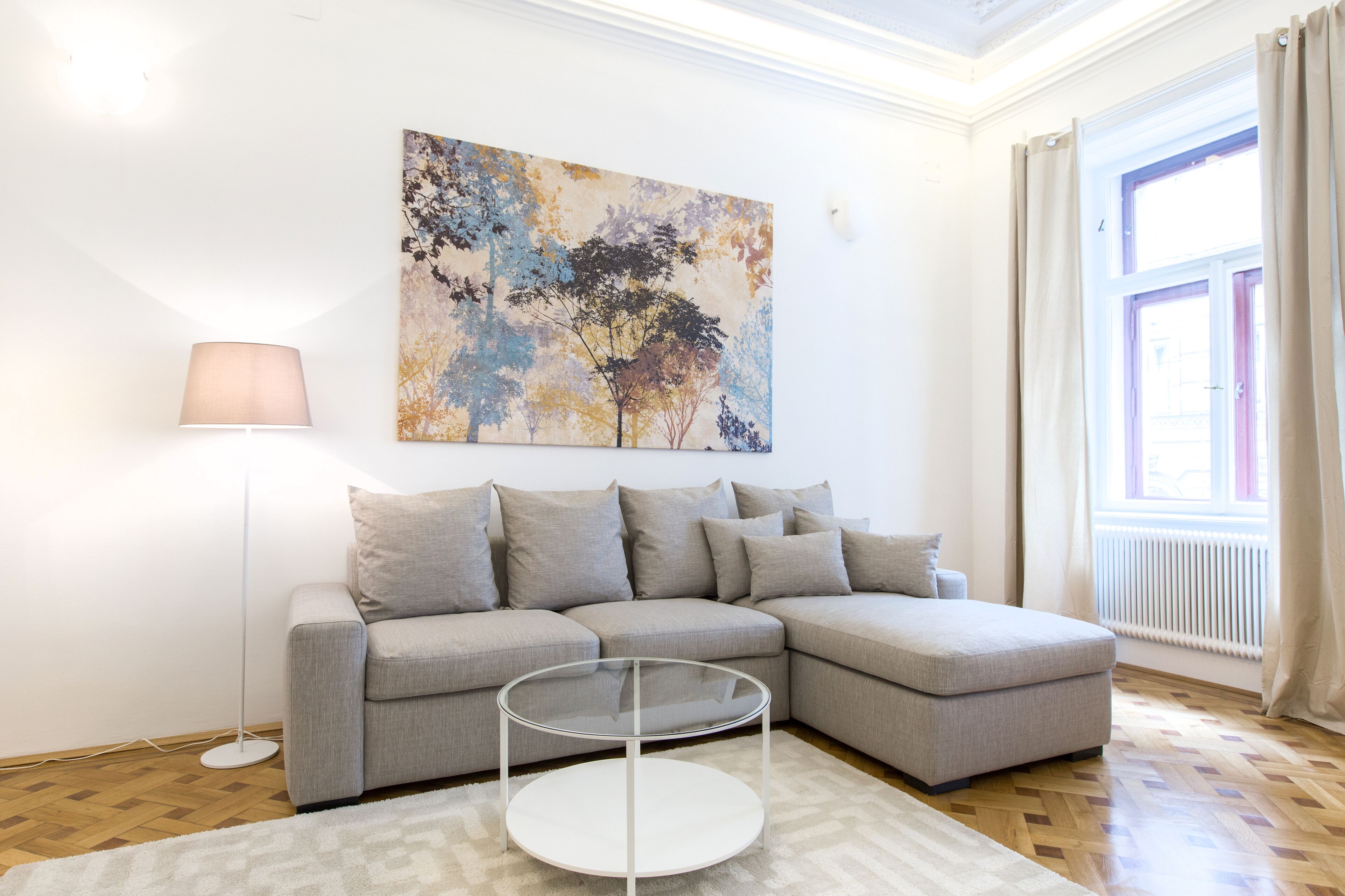 A modern living room with a grey sectional sofa, a glass coffee table, and a floor lamp.