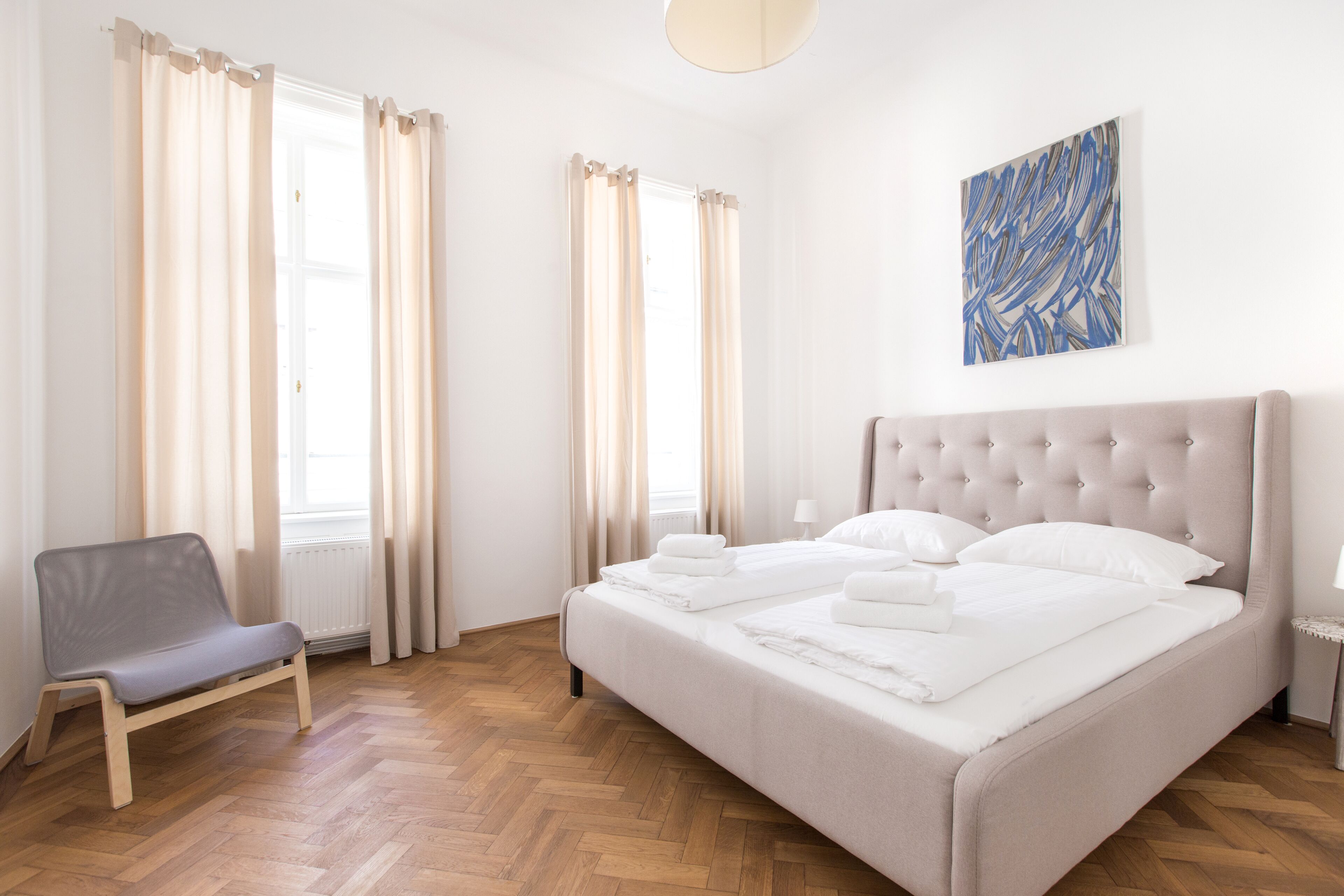 A bedroom with a bed, a chair, and a window with curtains.