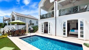 A two-story house with a swimming pool, outdoor furniture, and a balcony. - Villa with Pool & Golf Views - Coral Blu (2 bed) (Westmoreland)
