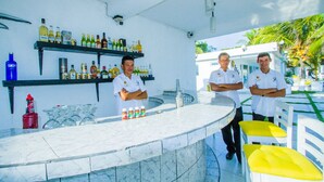 A bar area with a marble countertop, shelves with bottles, glasses, and a sink. - Hotel La Casona Beach (Iztapa)