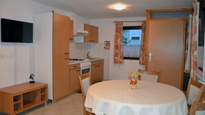 A compact kitchen with wooden cabinets, a built-in oven, and a dining table with chairs. - Lenardic Bled apartments for 5 person.  (Bled)