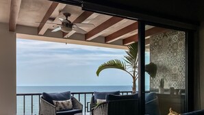 Un balcon doté de meubles en osier, d’un ventilateur de plafond et offrant une vue sur l’océan.