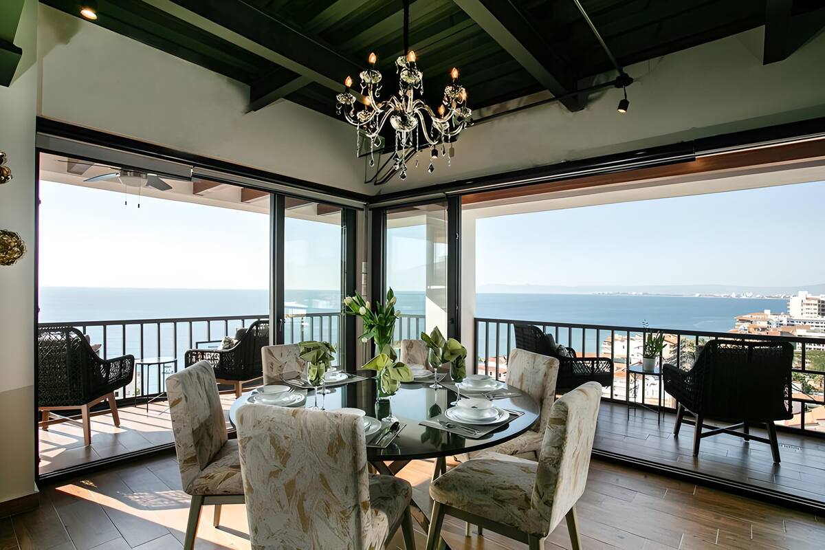 Un espace repas avec vue sur la mer, de grandes fenêtres et un lustre.