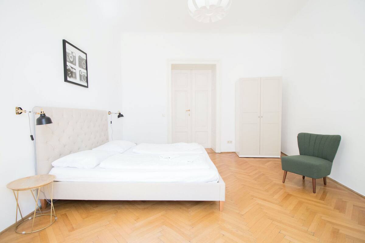 A bedroom with a bed, a chair, a wardrobe, and a lamp.