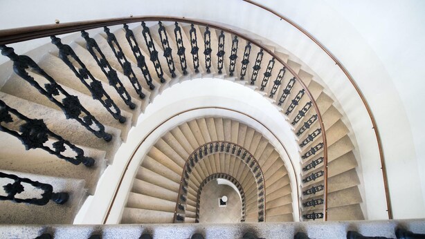 A spiral staircase with a white interior and black balusters. - HeyMi Apartments Stadtpark (Vienna)