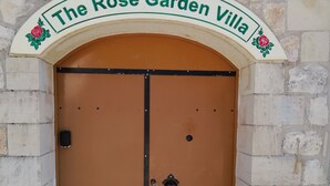 Una puerta marrón con manija negra y mirilla, enmarcada por un muro de piedra con tejado de tejas rojas.