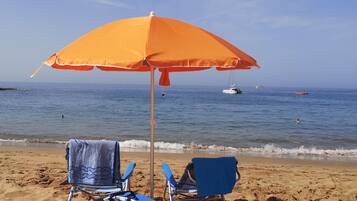 Vlak bij het strand, ligstoelen aan het strand, parasols, strandlakens