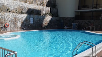 Een buitenzwembad, ligstoelen bij het zwembad