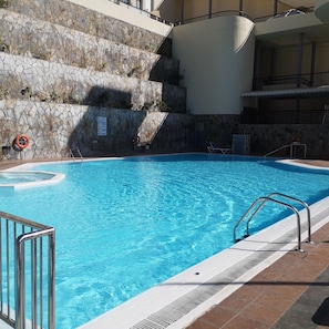 Una piscina al aire libre, sillones reclinables de piscina