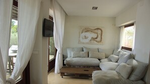 A room with a sectional sofa, a mounted TV, and a painting on the wall. - Spectacular tower in front of the sea (L' AMETLLA DE MAR)
