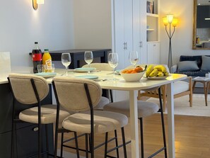 A modern dining area with a round table, four chairs, and a bowl of fruit. - L'appartement Magdebourg (Paris)