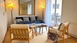Un salon comprenant un canapé, deux fauteuils, une table basse et un grand miroir.