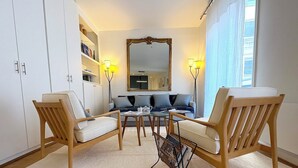 Un salon moderne avec deux fauteuils en bois, un canapé, une table basse et un grand miroir.