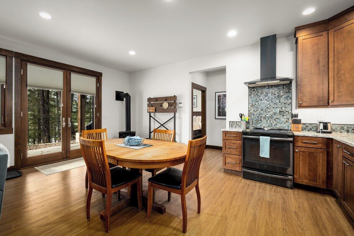 A modern kitchen with wooden cabinets, a large stove, and a dining area with a wooden table and chairs.