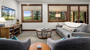 Ein Wohnzimmer mit grauem Sofa, einem runden Couchtisch und einem Bücherregal.