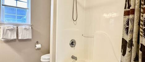 Un baño con ducha, inodoro y ventana.