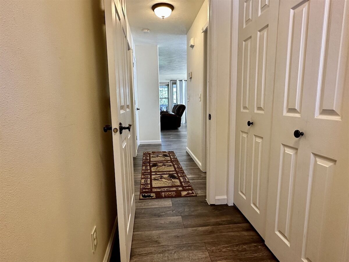 A hallway with wooden flooring and white doors.