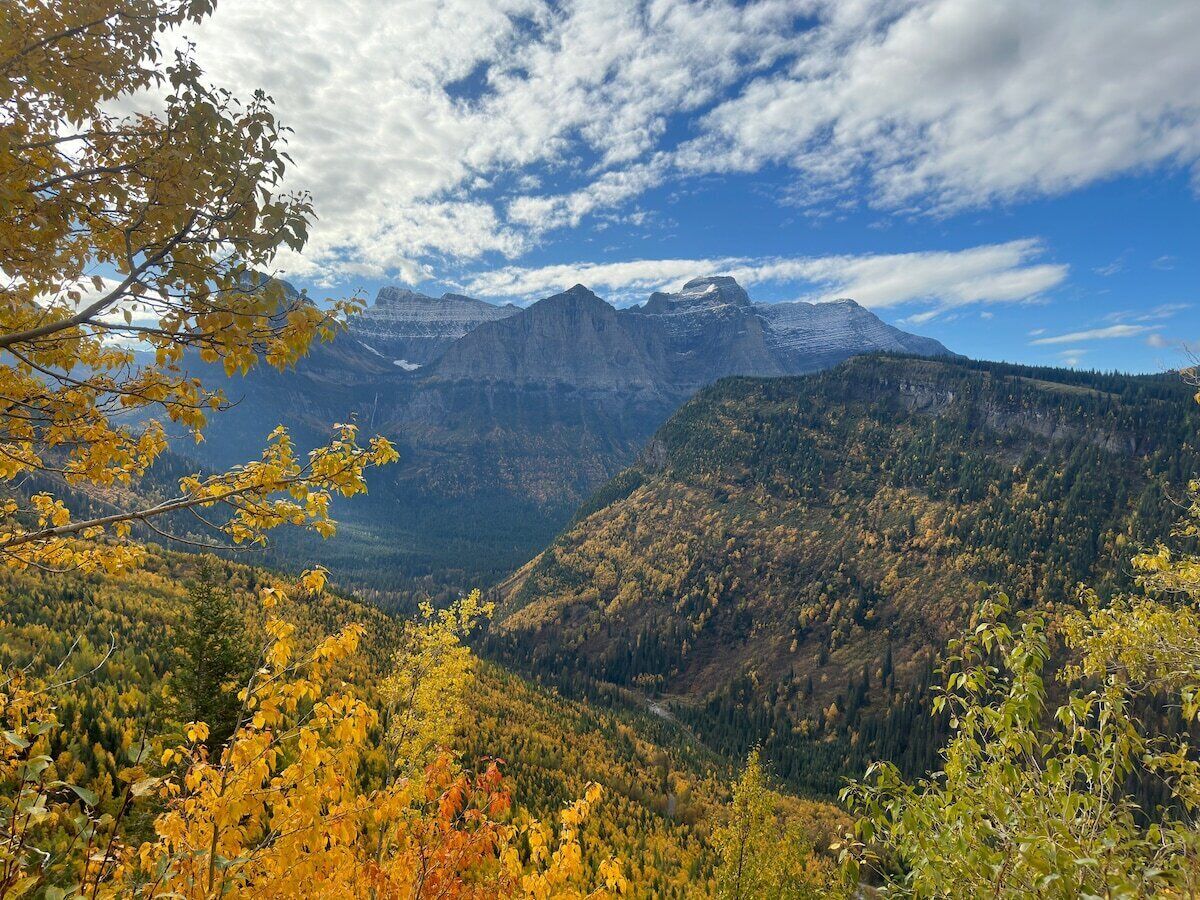 Paisaje montañoso con follaje otoñal y cielo despejado.