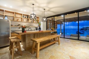 A modern kitchen with wooden countertops, a built-in bench, and pendant lighting.
