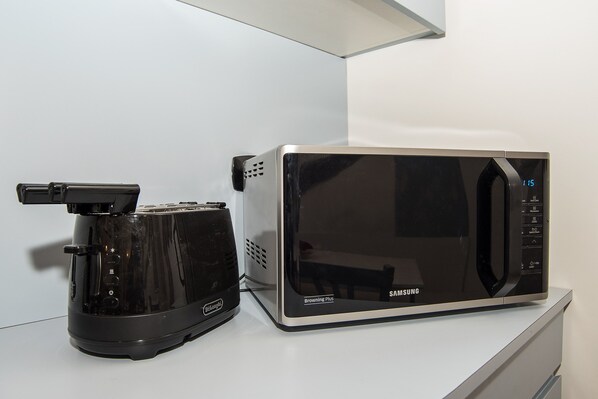 A microwave oven with a digital display and a toaster on a white countertop. - LikeYourHome, 80 sq m luxury apartment with Jacuzzi, in Trastevere district (Roma)