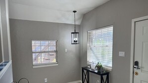 A hallway with two windows, a door, and a console table with a plant.
