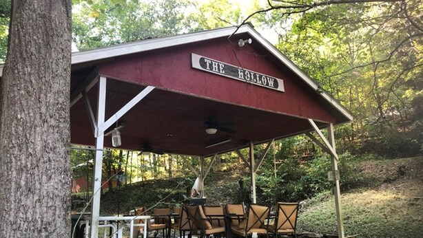 A covered pavilion named "The Hollow" with outdoor seating and a rustic design.