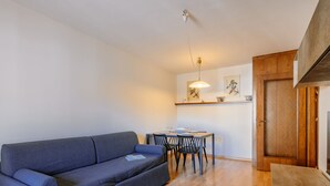 En moderne stue med en grå sofa, et spisebord med stole og et træskab.