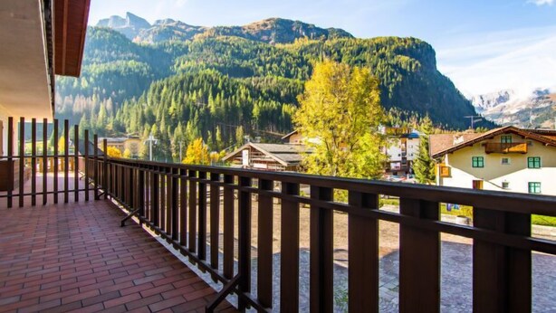 En balkon med udsigt over et bjerglandskab og en landsby nedenfor.