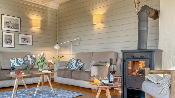 Ein gemütliches Wohnzimmer mit Sofa, Couchtisch und Kaminofen.