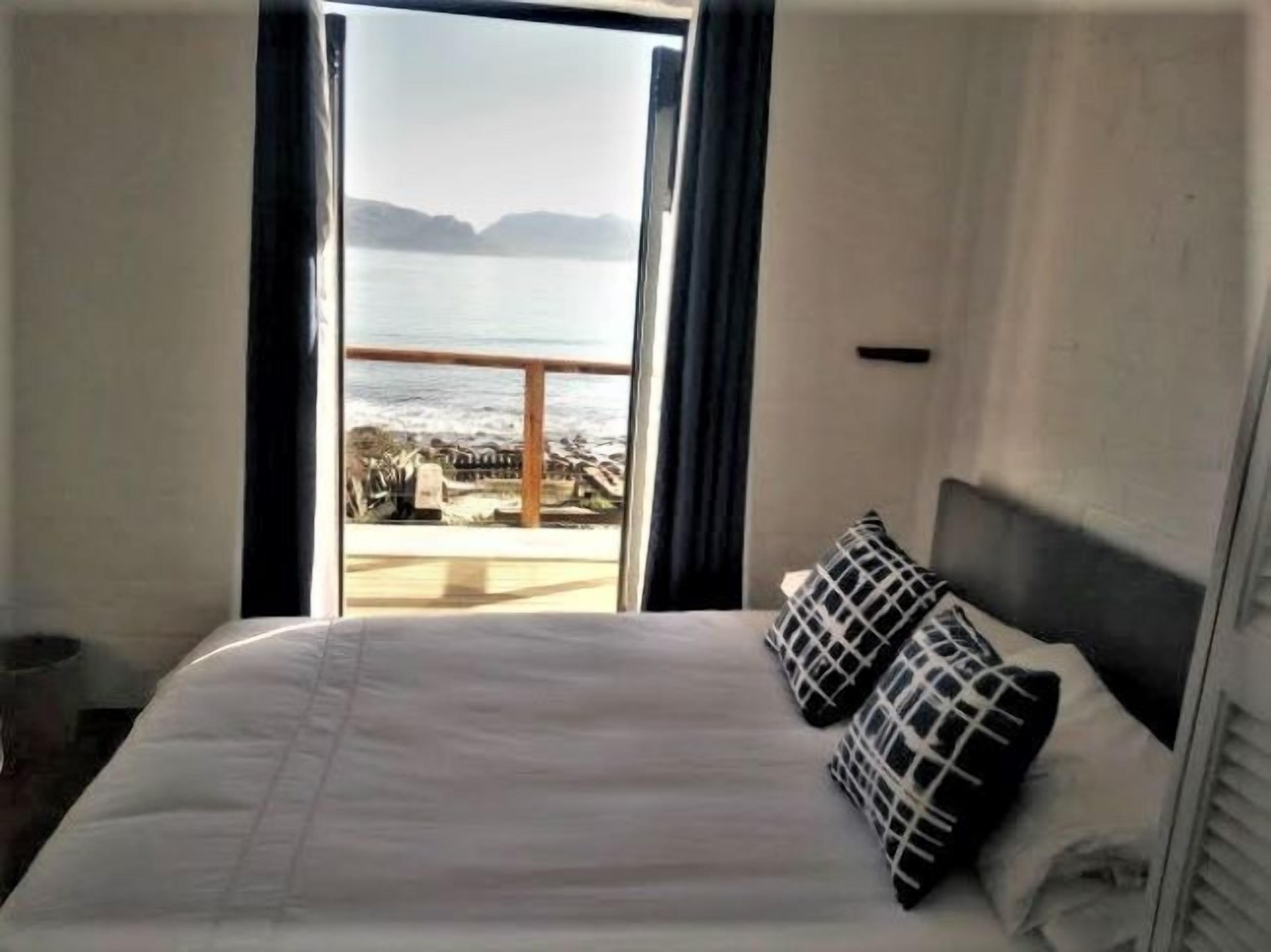 Een hotelkamer met een bed, uitzicht op zee en een balkon.
