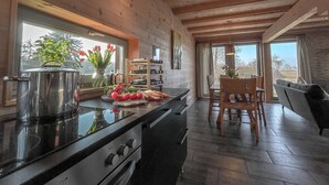 Een moderne keuken met een groot eiland, houten balken en uitzicht op de omgeving.