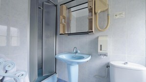 Un baño con ducha, lavamanos, inodoro y barra para toallas.