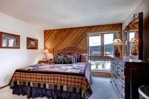 A bedroom with a large bed, a dresser, and a window with a view of a town. - Cimarron - great condo! Slopes and town within easy walking distance  (Breckenridge)