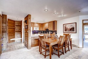 A modern kitchen with wooden cabinets, a dining table with chairs, and a view of the outdoors. - Cimarron - great condo! Slopes and town within easy walking distance  (Breckenridge)