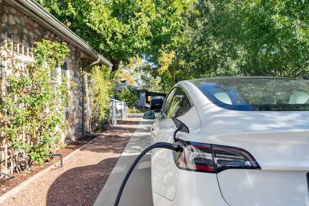 Um carro branco estacionado em uma estação de carregamento para veículos elétricos.