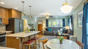 A modern kitchen with wooden cabinets, a central island, and a dining area with a round table and chairs.