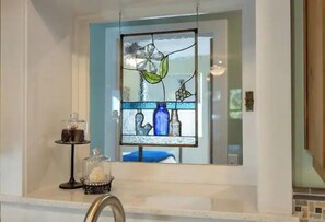 Bathroom features a sink, mirror, and stained glass window.