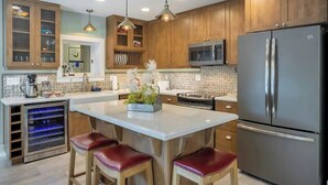 A modern kitchen with wooden cabinets, stainless steel appliances, and pendant lighting.