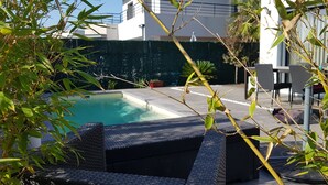 A pool area with a clear view of the pool, surrounded by greenery and modern outdoor furniture. - Chambre Cosy (Agde)