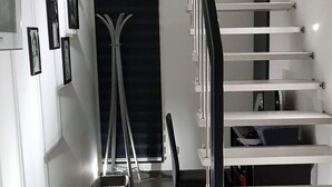 A modern staircase with a minimalist design, leading to a dark room with a large window. - Chambre Cosy (Agde)